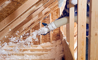 contractor with tube blowing insulation into home attic